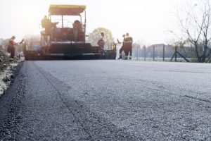 Workers placing new coating of asphalt on the road.